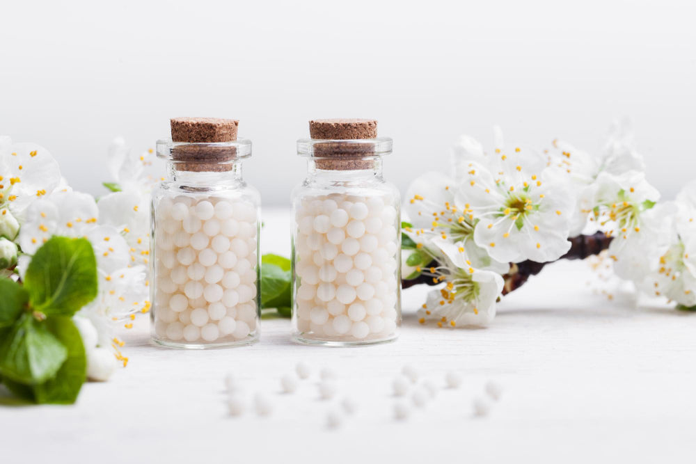 Imagem de cápsulas de suplemento num recipiente, com uma mão a pegar numa cápsula, representando o uso de suplementos ou preparados naturais.