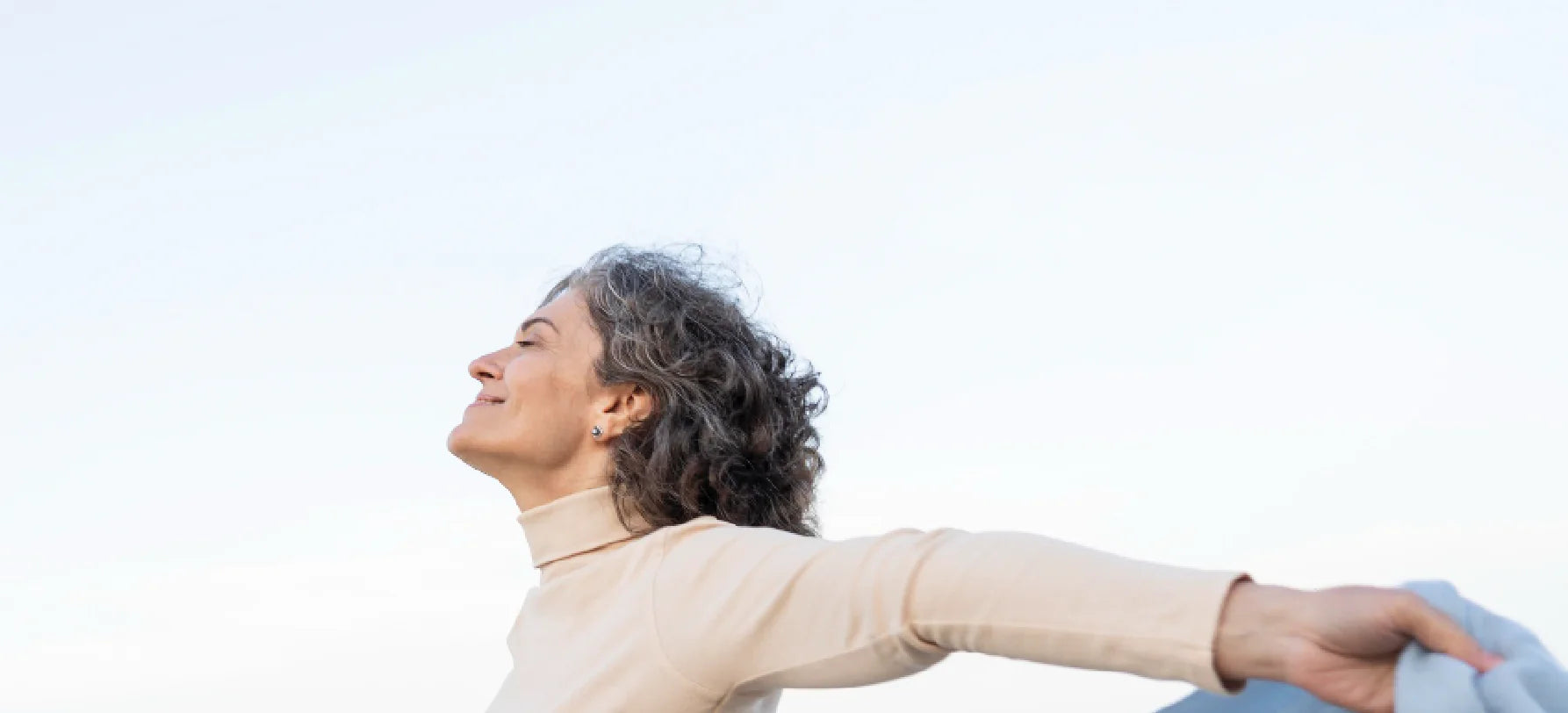 Mulher em momento de bem-estar ao ar livre, transmitindo equilíbrio, vitalidade e qualidade de vida.