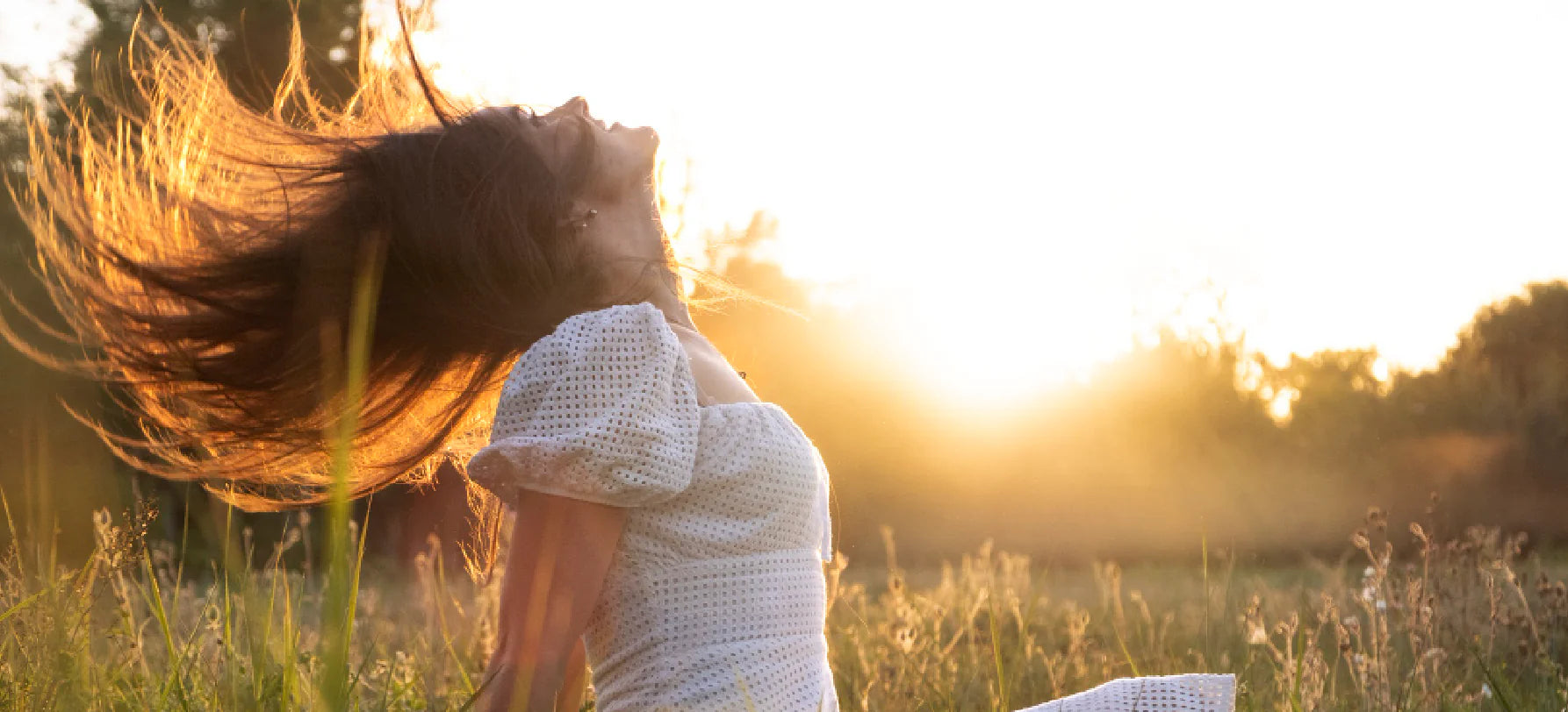Mulher ao ar livre em contacto com o sol, transmitindo energia, vitalidade e bem-estar natural.