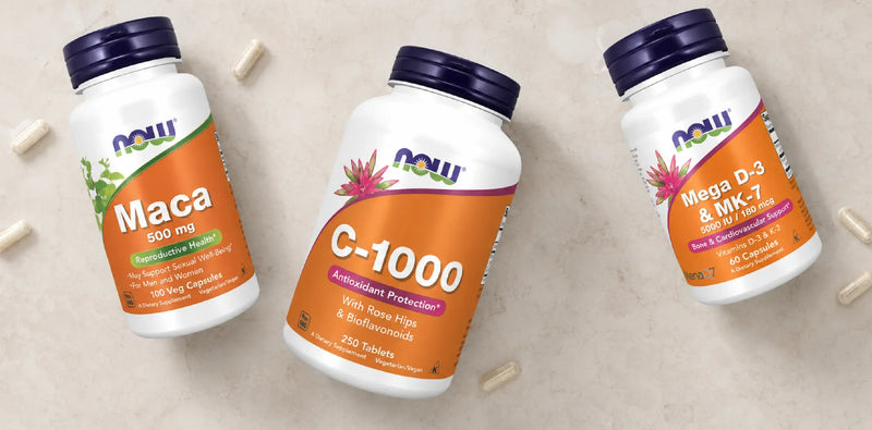 Suplementos NOW Foods Maca 500 mg, Vitamina C-1000 e Mega D-3 & MK-7, apresentados sobre fundo claro com cápsulas dispersas.