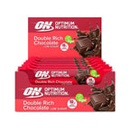 Barra de Proteína Vegan Duplo Chocolate 12 x 60gr Optimum Nutrition, snack proteico vegetal com 18g de proteína e baixo teor de açúcar.
